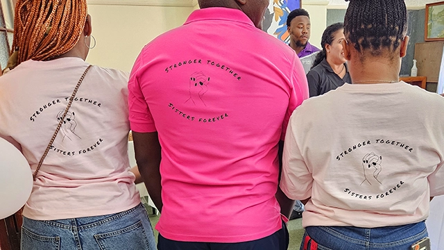 Male House Warden with students wearing t-shirts printed "Stronger Together, Sisters Forever."