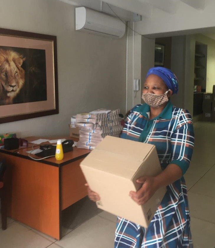 CSD Staff member Nolly carrying box of food parcels to the delivery truck. 