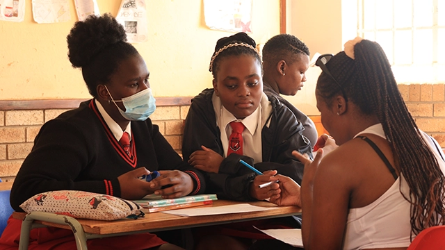 A mentor works with two mentees as part of the 9/10ths programme