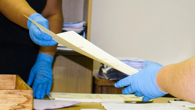 Academic Administration staff and student helpers wear gloves when handling parchments to ensure they remain pristine for graduates [CREDIT: Rikie Lai]