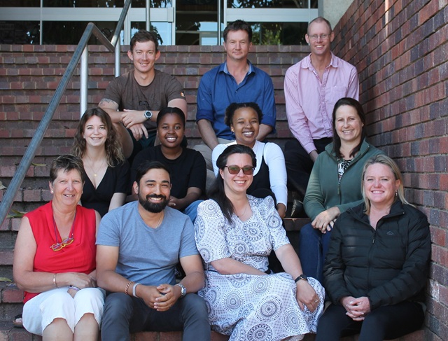 HKE staff members and student assistants sit on the steps leading up to the Department's building