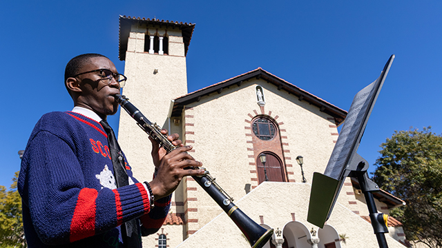 Musa Makgato playing his clarinet on St Peter's lawns, with the Rhodes Chapel in the background. [PIC CREDIT: Vusumzi Tshekema
